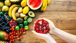 手捧石榴与多彩水果