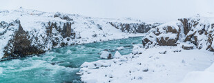 冰雪覆盖下的碧绿湍急河流