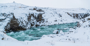 冰雪覆盖下的碧绿湍急河流