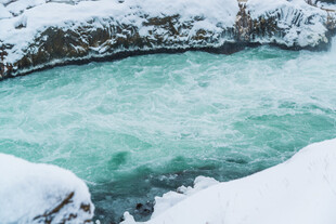 冬日冰雪环绕的碧绿湖水