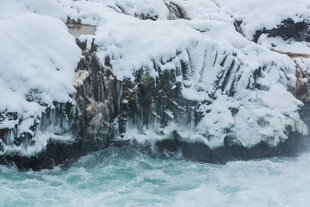 雪覆岩石旁的湍急水流