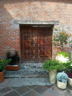 古朴砖墙旁的木门与绿植