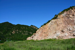 山间裸露岩壁与葱郁草地