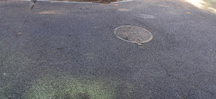 阳光斑驳的地面上与下水道井盖