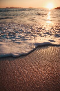 夕阳下的海浪轻拍沙滩