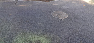 阳光洒落的沥青地面与井盖