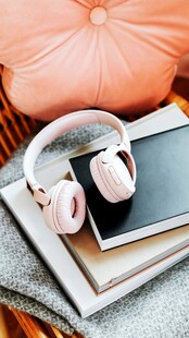 粉色耳机置于书籍平板之上