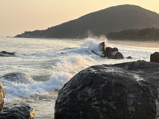 夕阳下海浪拍打礁石美景