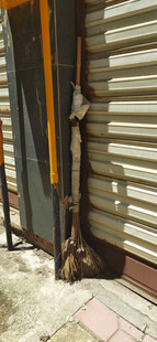 老旧卷帘门一角的破旧扫帚