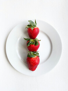 三颗草莓摆放在白色盘子上