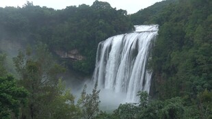 壮观瀑布隐于葱郁山林间