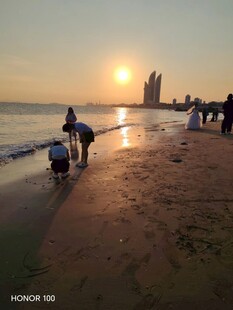 夕阳下的海边漫步人群