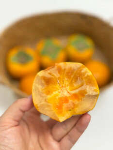 手捧剥开的新鲜甜柿子