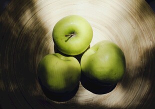 三个青苹果置于盘中