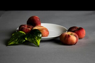 白盘上的鲜嫩桃子与绿叶