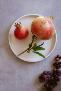 白盘上的新鲜石榴及枝叶