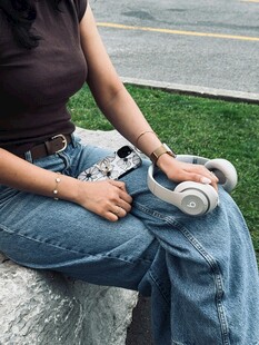 女子坐石上把玩白色耳机