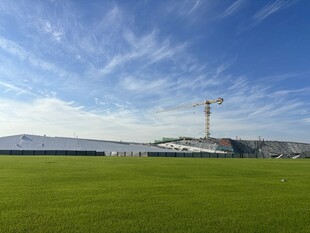 绿茵场地与远处塔吊景观