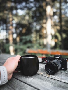 户外木桌上的相机与咖啡杯