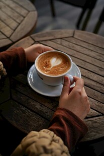 手捧精美拉花咖啡的惬意时刻