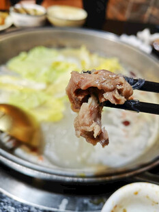 筷子夹起锅中鲜嫩牛肉