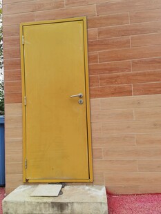 黄色金属门置于砖墙旁