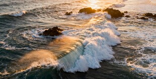 夕阳下海浪拍击礁石