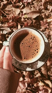 手捧热饮享秋日惬意时光