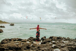 海边岩石上张开双臂的人