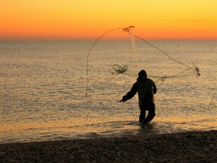 海边黄昏渔夫撒网瞬间