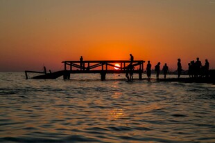 夕阳下海边栈桥的人群