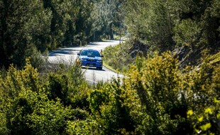 林间公路上行驶的蓝色汽车