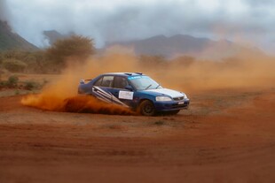 蓝车在泥地飞驰扬起尘土