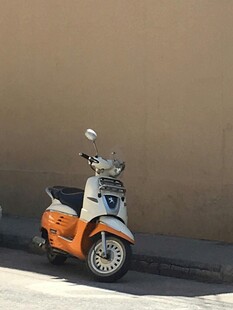 复古橙色小摩托靠墙而立
