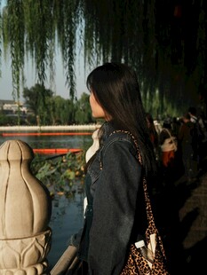 女子赏景于湖畔垂柳旁