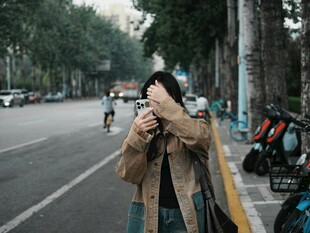 街头女子手持相机专注拍摄