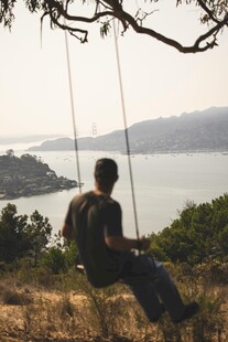 男子坐秋千赏湖景风光