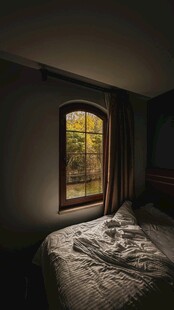 昏暗卧室中窗边凌乱床铺