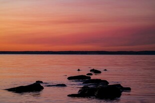 夕阳下宁静的水面与礁石