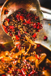 香辣调料正从勺中洒落在麻椒鸡上