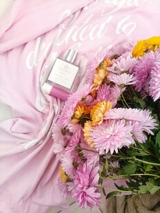 粉色布上的多彩鲜花与香水瓶