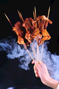 手持冒烟美味烤牛蛙串