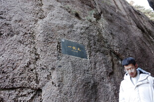 男子立于刻字山石旁