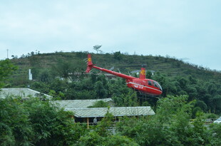 红色直升机飞越绿树山丘