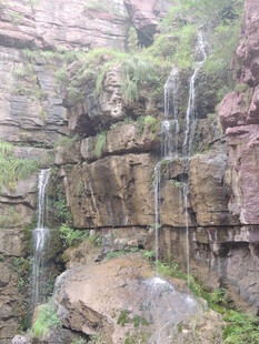 山间瀑布垂落于嶙峋岩壁