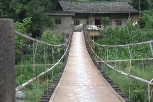 乡村吊桥通向古朴小屋