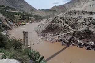 山间悬索桥横跨浑浊河流