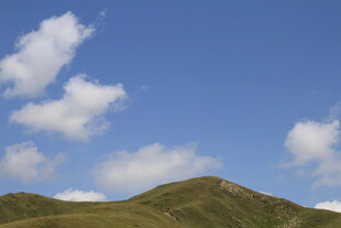 蓝天白云下的翠绿山丘