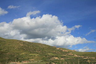 蓝天白云下的翠绿山坡