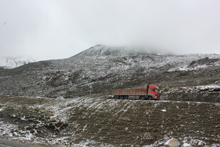 雪山间行驶的红色卡车